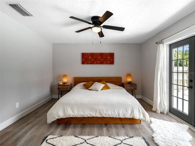 bedroom featuring visible vents, a textured ceiling, wood finished floors, access to outside, and baseboards