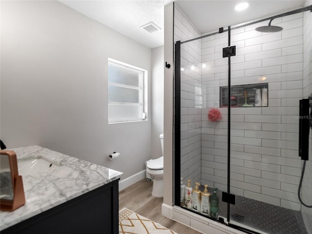 full bath featuring a stall shower, visible vents, toilet, wood finished floors, and vanity