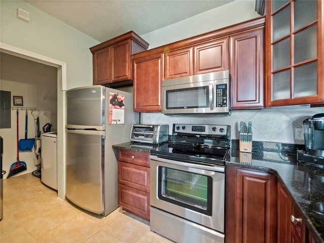 kitchen featuring tasteful backsplash, stainless steel appliances, dark stone counters, and light tile patterned flooring