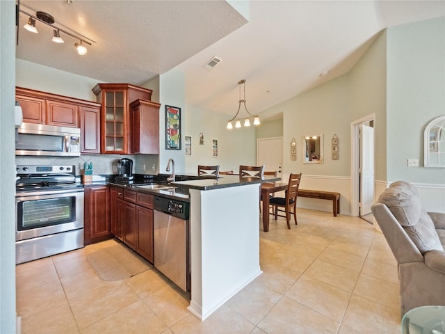 kitchen with stainless steel appliances, kitchen peninsula, pendant lighting, sink, and light tile flooring