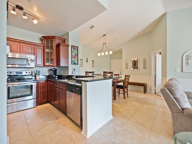 kitchen featuring appliances with stainless steel finishes, decorative light fixtures, kitchen peninsula, and sink