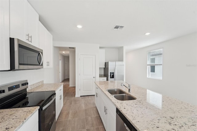 kitchen featuring stainless steel appliances, white cabinets, sink, and light stone countertops