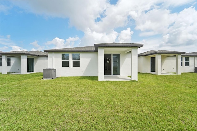 rear view of property featuring a yard, central AC unit, and a patio area