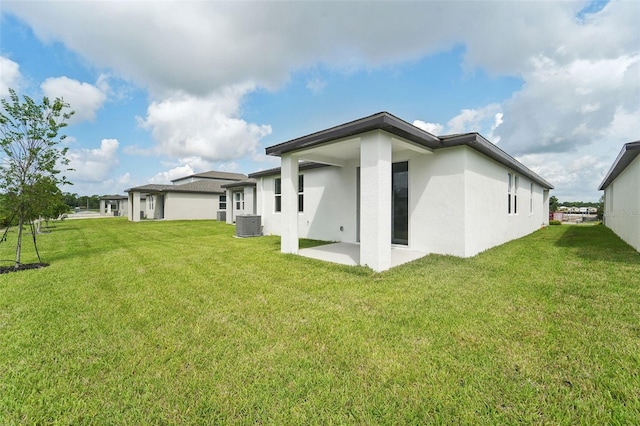 rear view of house featuring a patio, central air condition unit, and a lawn