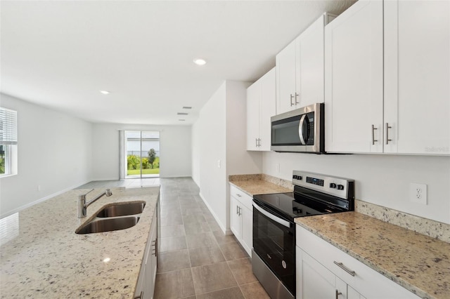 kitchen with sink, white cabinets, light stone countertops, and appliances with stainless steel finishes