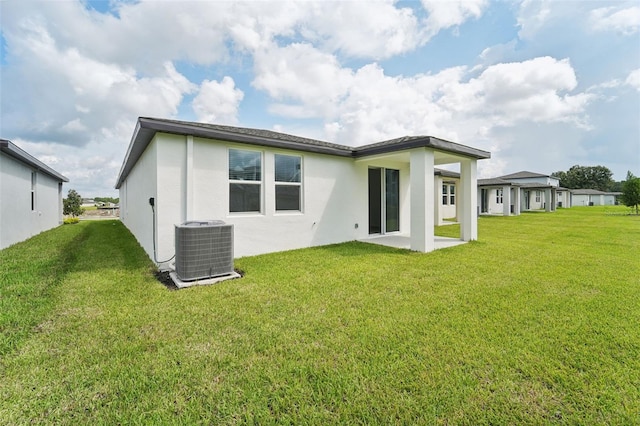 rear view of property with a patio area, central AC unit, and a lawn