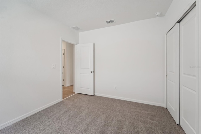 unfurnished bedroom featuring a closet and light colored carpet