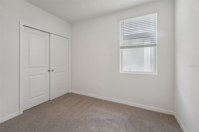 unfurnished bedroom featuring a closet and light colored carpet