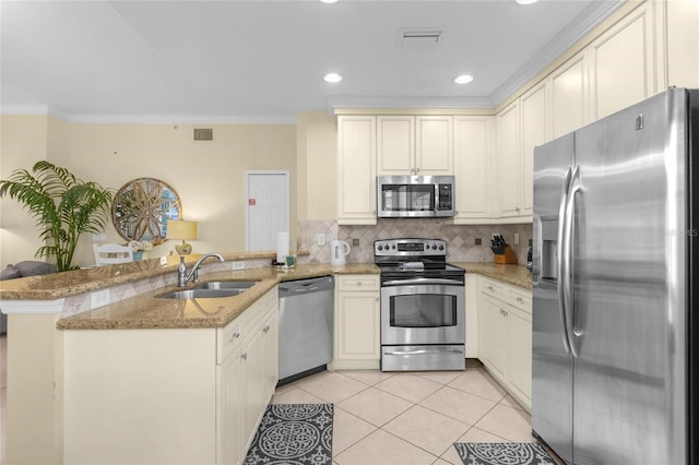 kitchen featuring kitchen peninsula, decorative backsplash, sink, appliances with stainless steel finishes, and light stone counters