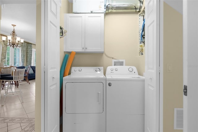 washroom with tile patterned flooring, a notable chandelier, separate washer and dryer, and cabinets