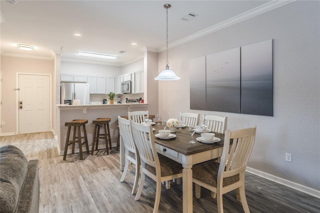 dining room featuring light hardwood / wood-style floors and crown molding