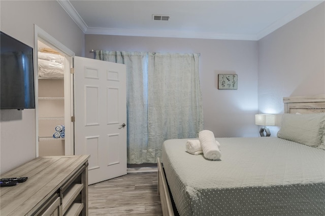 bedroom with ornamental molding and hardwood / wood-style flooring