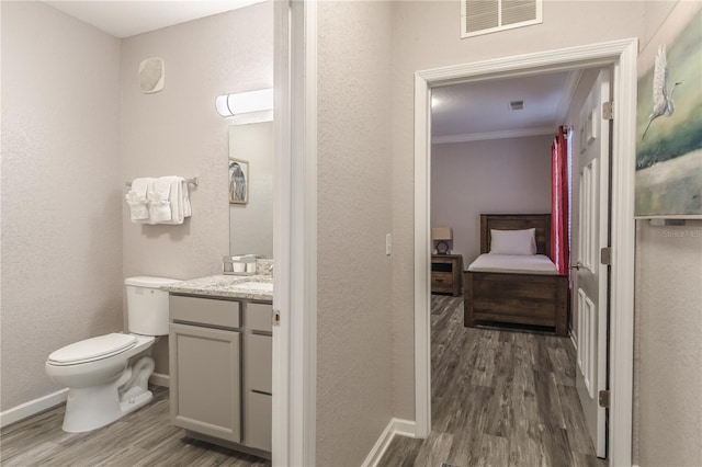 bathroom with crown molding, hardwood / wood-style flooring, toilet, and large vanity