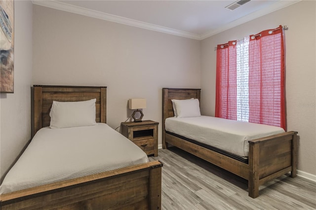 bedroom featuring light hardwood / wood-style floors, ornamental molding, and multiple windows