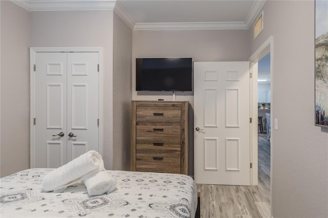 bedroom with ornamental molding, a closet, and light wood-type flooring