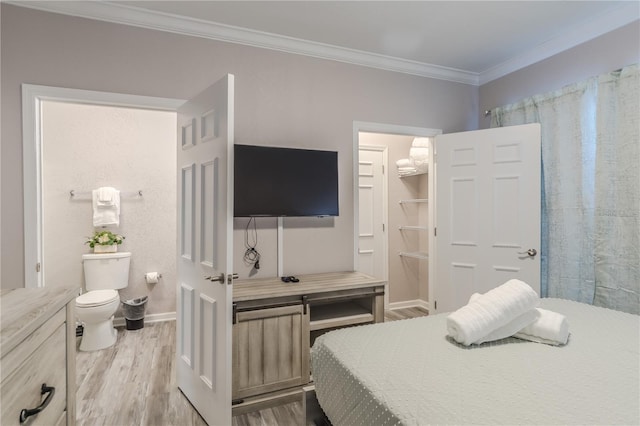 bedroom with a spacious closet, light hardwood / wood-style flooring, and crown molding