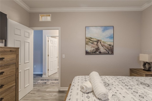 bedroom featuring ornamental molding and light wood-type flooring