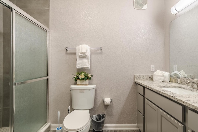 bathroom featuring oversized vanity, toilet, and a shower with door