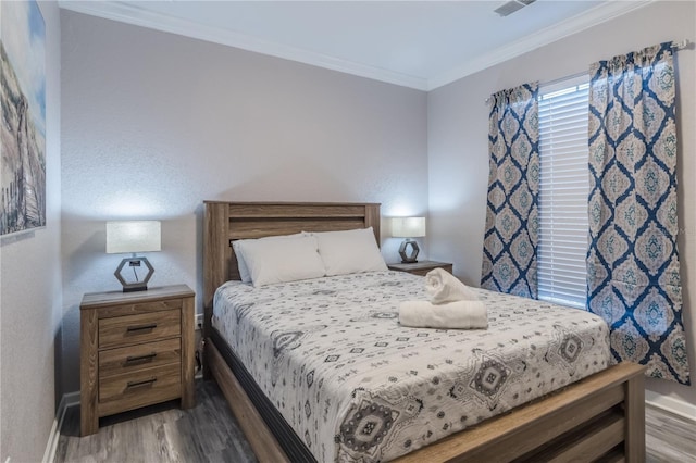 bedroom with ornamental molding and hardwood / wood-style floors