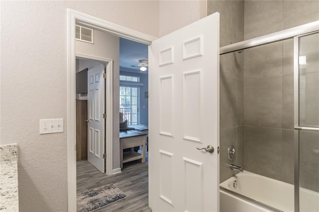 bathroom with shower / bath combination with glass door, wood-type flooring, and ceiling fan