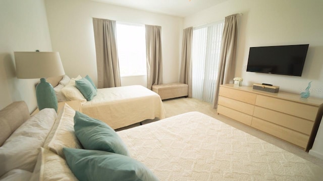 bedroom with light carpet and multiple windows