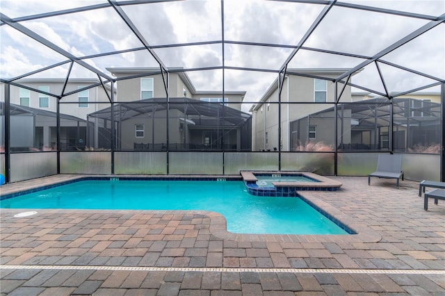 view of swimming pool featuring a patio, glass enclosure, and an in ground hot tub