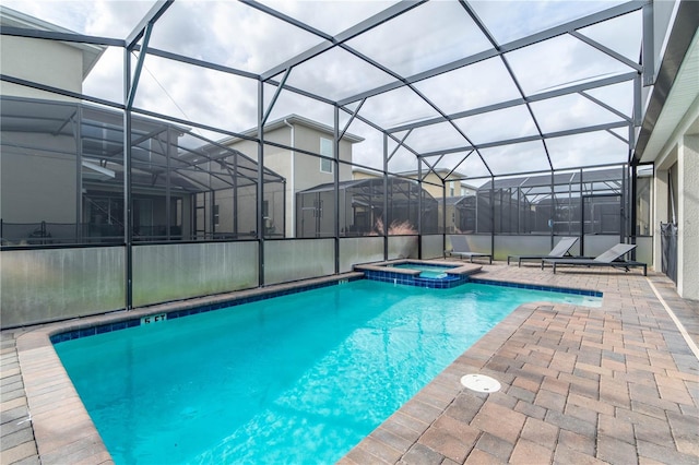 view of pool with glass enclosure, a patio, and an in ground hot tub