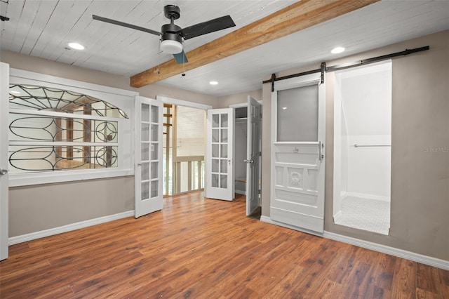 interior space with french doors, ceiling fan, beam ceiling, a barn door, and wood-type flooring