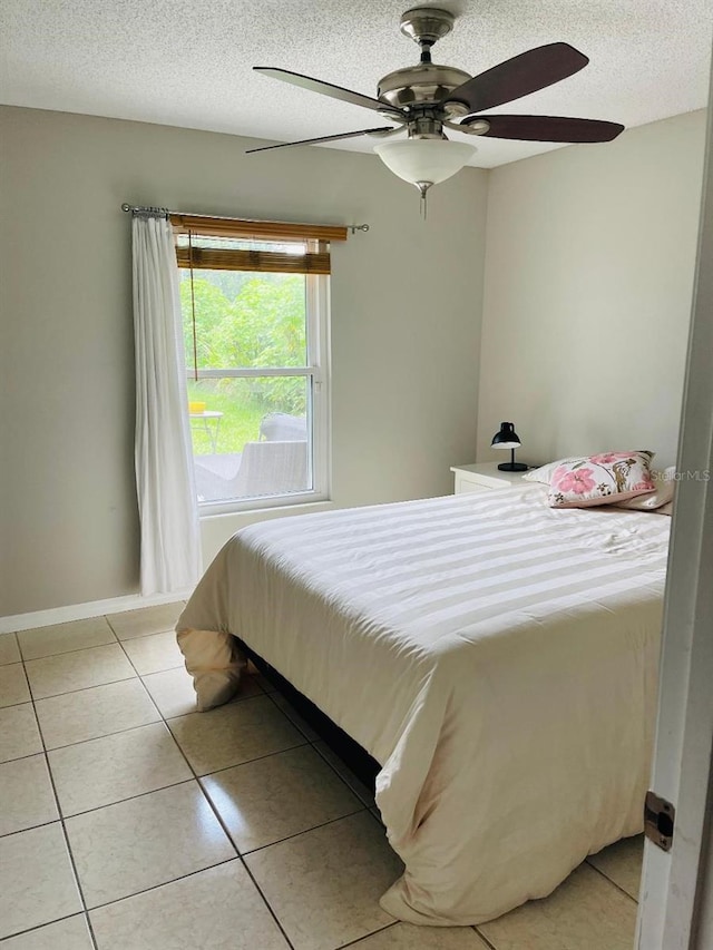 tiled bedroom with ceiling fan and a textured ceiling