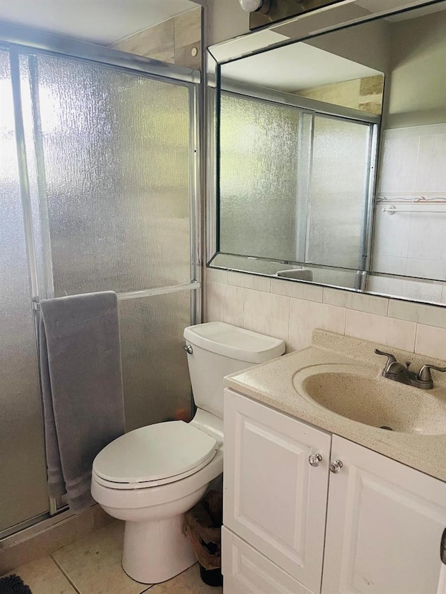 bathroom with tile walls, vanity with extensive cabinet space, a shower with door, tasteful backsplash, and toilet