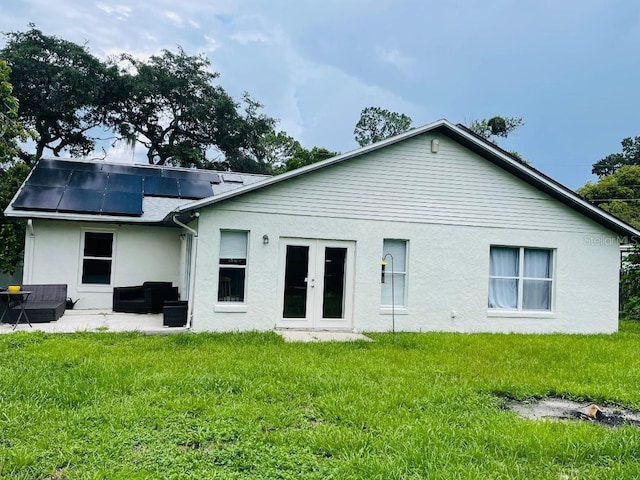 back of property with a patio area, french doors, solar panels, and a yard