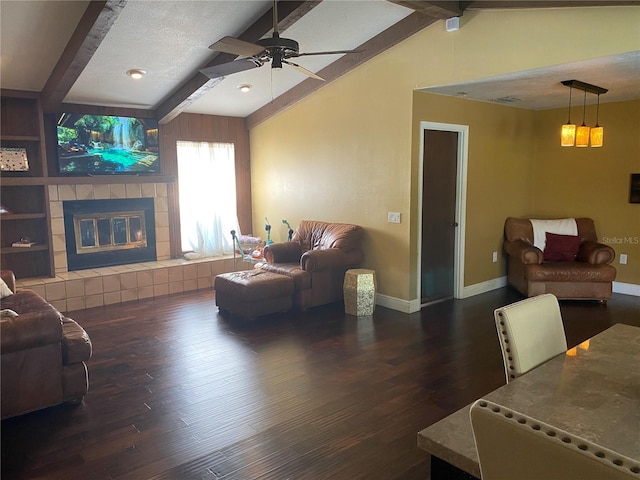 living room with ceiling fan, dark hardwood / wood-style floors, lofted ceiling with beams, and a tile fireplace