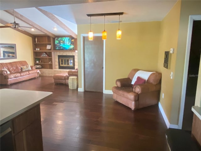 living room featuring lofted ceiling with beams, ceiling fan, dark wood-type flooring, a fireplace, and built in features