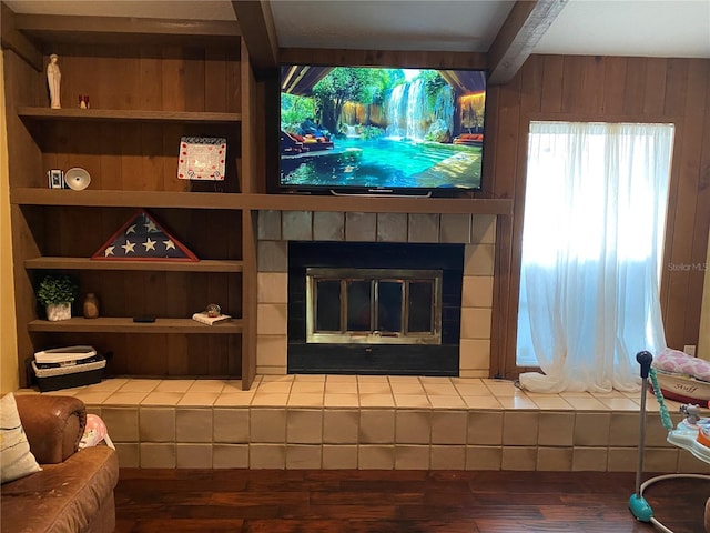 room details featuring wood-type flooring, beamed ceiling, and a tiled fireplace