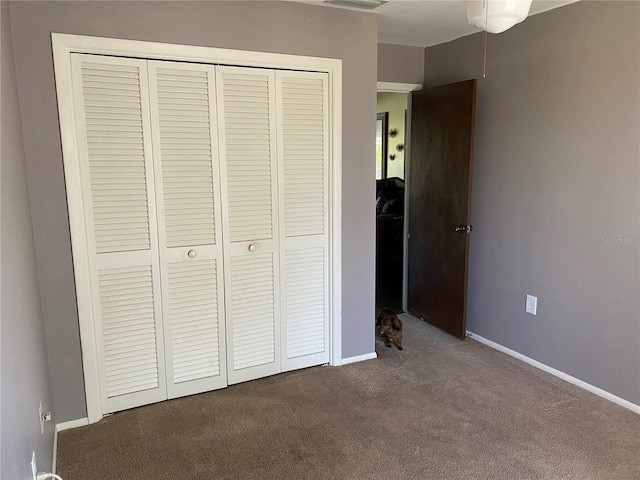 unfurnished bedroom with a closet and dark colored carpet