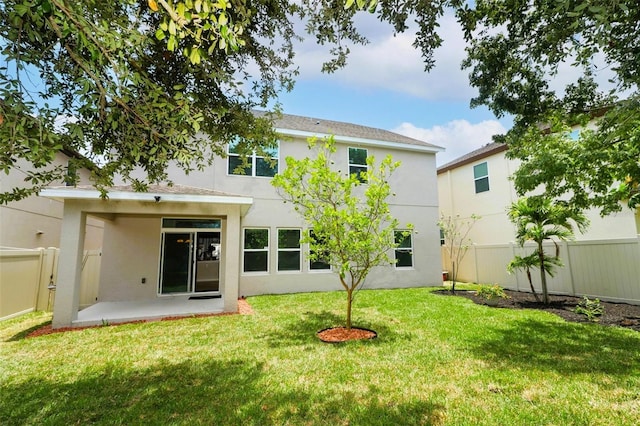 rear view of house featuring a lawn and a patio