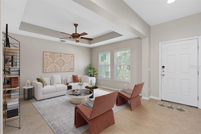 tiled living room featuring ceiling fan and a raised ceiling