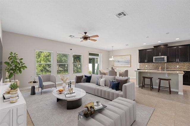 tiled living room featuring ceiling fan with notable chandelier