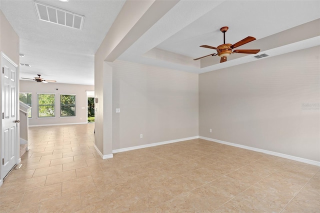 unfurnished room featuring ceiling fan, light tile patterned floors, and a tray ceiling