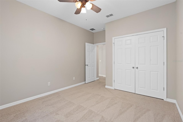 unfurnished bedroom featuring ceiling fan, light colored carpet, and a closet