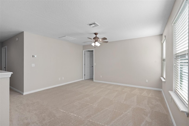 unfurnished room featuring a textured ceiling, ceiling fan, and light colored carpet