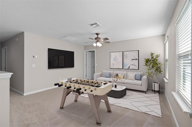 recreation room with ceiling fan, a wealth of natural light, and light colored carpet