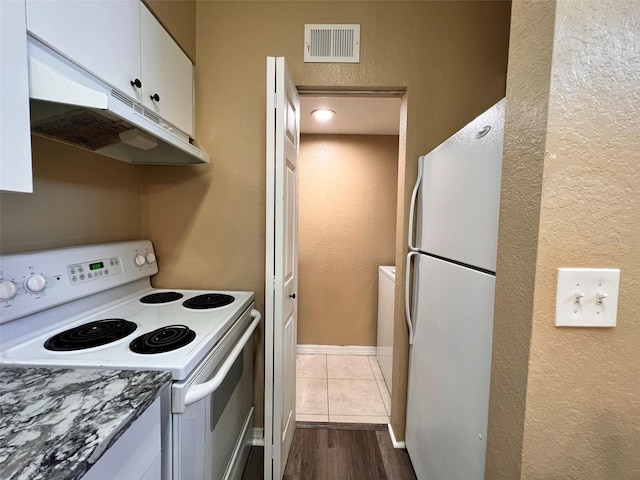 kitchen featuring hardwood / wood-style flooring, white appliances, and white cabinets