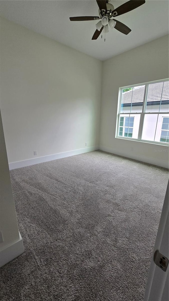 carpeted spare room featuring ceiling fan