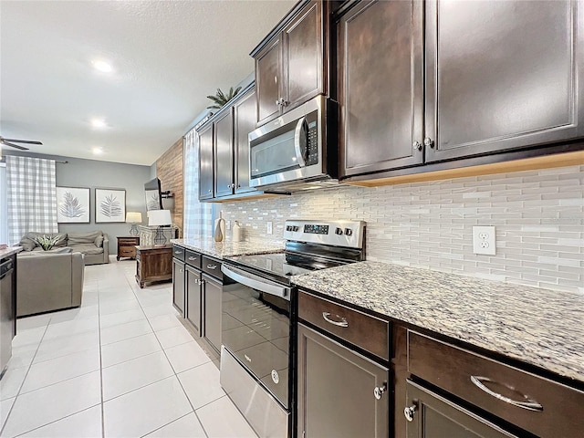 kitchen with light stone countertops, appliances with stainless steel finishes, decorative backsplash, dark brown cabinets, and light tile patterned flooring