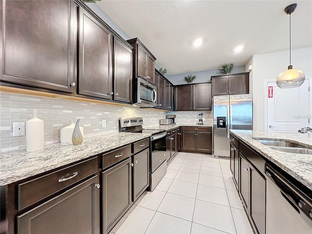 kitchen featuring dark brown cabinetry, sink, hanging light fixtures, decorative backsplash, and appliances with stainless steel finishes