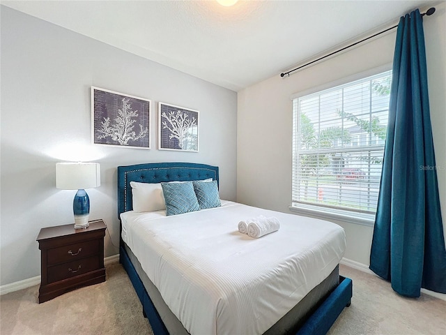 bedroom with light colored carpet and multiple windows