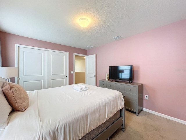 carpeted bedroom with a textured ceiling and a closet