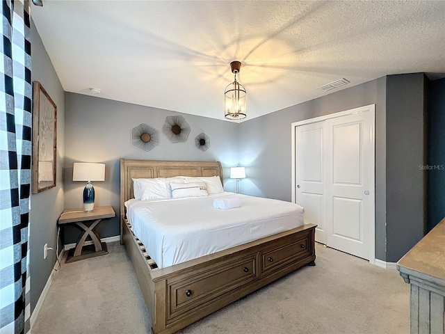 carpeted bedroom with an inviting chandelier, a textured ceiling, and a closet