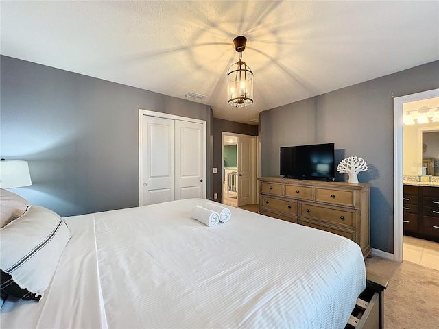 bedroom featuring a notable chandelier, light carpet, connected bathroom, and a closet